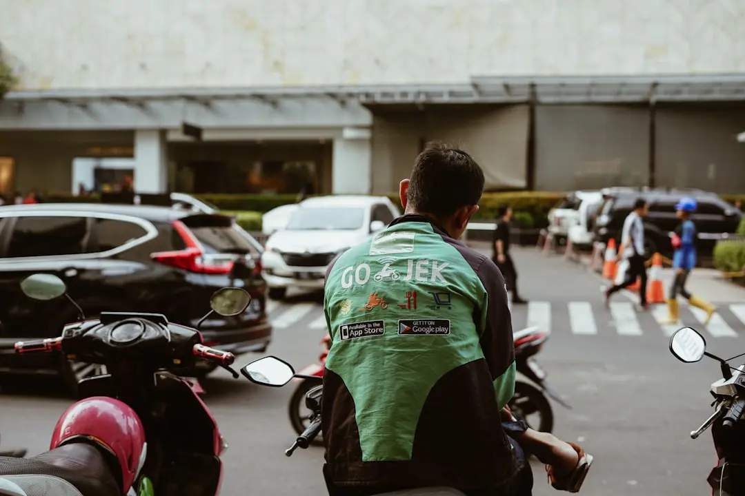 man sitting on motorcycle — Gojek driver waiting for passenger. Gojek is Indonesian transportation startup