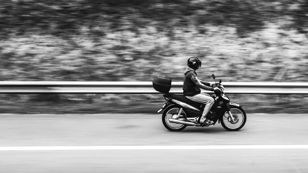 A black and white photo of a person riding a motorcycle — "FlipFlops" Scooters are ubiquitous in Asia, zipping through every street and alley. In this warm, vibrant region, they provide a convenient and efficient way to commute, often with riders casually sporting flip-flops.