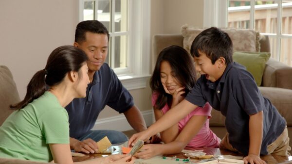 Família reunida jogando jogo de tabuleiro na mesa